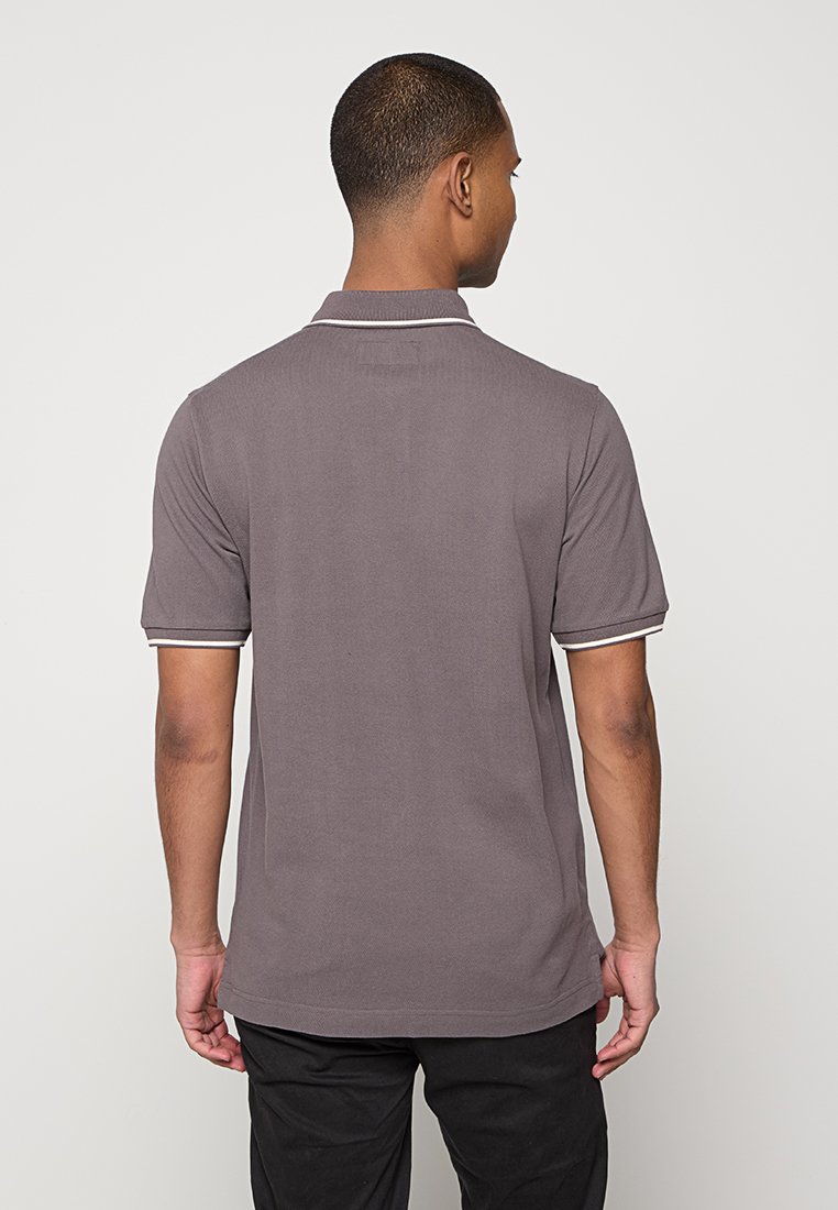 Szara koszulka polo z fakturowanej tkaniny, z krótkimi rękawami oraz białym wykończeniem na kołnierzyku i krawędziach rękawów, pokazana z tyłu.