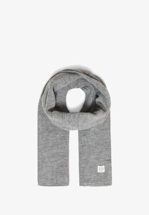 Écharpe en tricot grise pliée en boucle avec une petite étiquette en tissu blanche dans le coin inférieur droit sur un fond blanc.