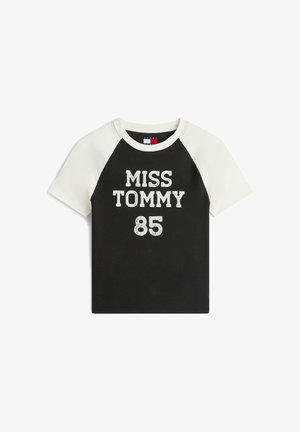 Maglietta nera con maniche raglan corte bianche, con la scritta "MISS TOMMY 85" in lettere bianche spesse e strutturate sul davanti.