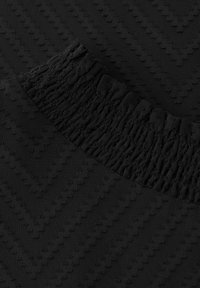Tela negra con un patrón texturizado en zigzag. Presenta una cintura elástica gatherada, superficie lisa y un color oscuro uniforme.