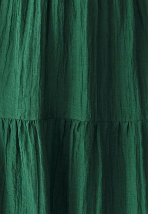 Green, textured fabric with vertical crinkles. Features gathered tiers along the hemline, creating a flowing appearance.