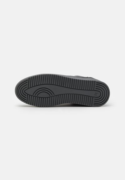 Musta kuminen sneaker-pohja, jossa on kuvioitu pinta. Sisältää sileän pinnan ja kaarevat linjat, suunniteltu tarjoamaan pitoa ja kestoa.