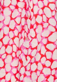 Camicia di cotone con un motivo astratto rosa e rosso caratterizzato da forme arrotondate, chiusura con bottoni e dettagli di cucitura a contrasto.