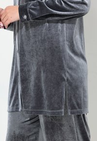 Grau Velours-Loungewear-Set mit einem Langarmtop mit seitlichem Schlitz und geknöpften Bündchen, kombiniert mit passender Hose mit elastischem Bund.