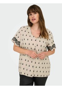 Beige gombos blúz fekete geometriai mintával és texturált fekete hímzett ujjal. Puha anyag, laza fazon és V-kivágás.