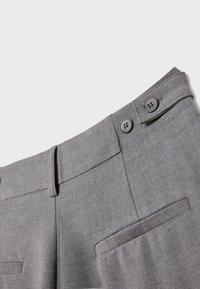Pantalon habillé gris avec deux boutons à la ceinture, passants pour ceinture et poches latérales présenté sur un fond uni.