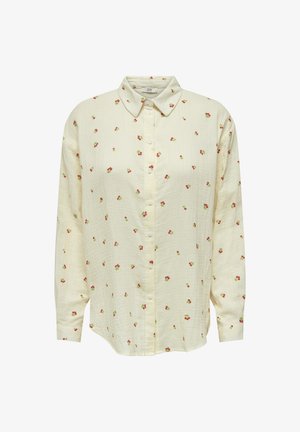 Light yellow button-up shirt made of textured fabric, featuring a collar and scattered floral print in red and green. Long sleeves.