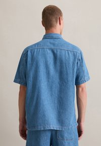 Denim overhemd met korte mouwen in lichtblauw, met een recht gesneden ontwerp, zachte textuur en een klassieke kraag met een achterste naaddetail.