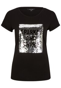 Camiseta negra de manga corta con cuello redondo que presenta un diseño rectangular de lentejuelas en plata, mostrando el texto "BRILLA Y DESTACA."