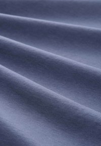 Modrá texturovaná tkanina s jemnými vlnami, která ukazuje měkký povrch a mírný lesk. Materiál vypadá lehký a hladký.