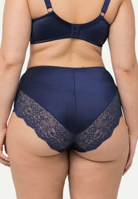 Marineblauwe lingerie set met een ribgebreide bh met verstelbare banden en een hooggeknotte slip met kantaccenten bij de benen.