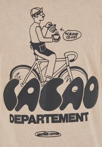 Beżowy bawełniany t-shirt z czarnym nadrukiem przedstawiającym osobę na rowerze trzymającą filiżankę kawy i rogalika, z napisem "CACAO DEPARTEMENT".