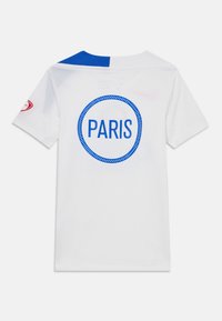 Hvit sportstrøye med et blått sirkulært "PARIS"-motiv på baksiden, med en kontrasterende blå aksent på skulderen. Myk tekstur.