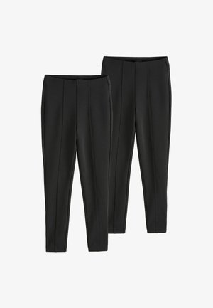 Black stretchy pants featuring a slim fit, tapered legs, and two front pleats on the waist. No visible hardware, smooth texture.