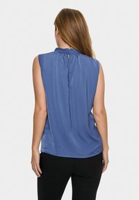Top blu senza maniche con scollatura arricciata e chiusura a bottone sul retro, realizzato in tessuto morbido, abbinato a un bottom nero.