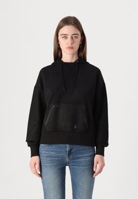 Felpa nera con tasca frontale, cappuccio con cordino e orlo a coste. Presenta una superficie liscia e morbida con dettagli di cucitura sottili.