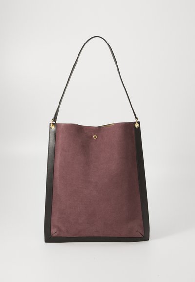 Suede tote taske i mørk burgunderrød med sort læderdetaljer, der har et enkelt design, en enkelt rem og rund knaplukning øverst.
