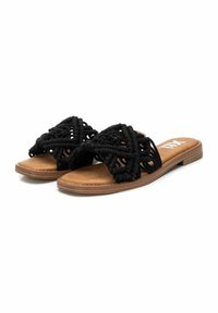 Sandalias planas negras con un diseño superior de macramé tejido, plantilla acolchada en tono marrón claro y suela flexible de color marrón claro.
