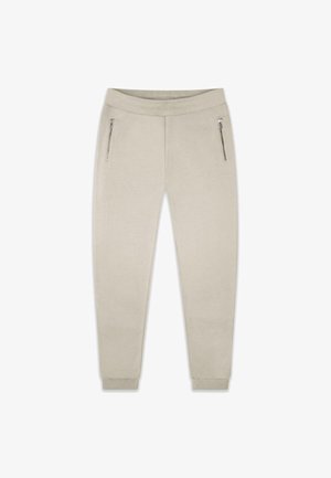 Pantalons de survêtement beiges avec jambes fuselées, taille élastique et deux poches zippées sur les côtés. Tissu lisse avec des poignets côtelés aux chevilles.