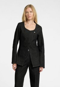 Svart denimjacka med långa ärmar, V-ringning och asymmetrisk nederkant. Har vit sömnad och en liten silverdetalj på bröstet.