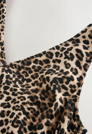 Leopardmönstrad tyg med en beige bakgrund och svarta fläckar, med en mjuk textur och breda axelband.