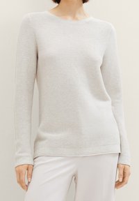 Maglione grigio chiaro a coste con maniche lunghe e scollatura a girocollo. Tessuto morbido, leggermente elasticizzato e vestibilità rilassata. Nessun motivo o accento visibile.