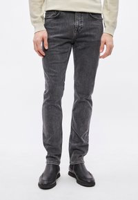 Γκρι τζιν από denim με στενή εφαρμογή, διακριτικές πιτσιλιές και αντίθετες ραφές. Συνδυασμένα με μαύρα δερμάτινα μποτάκια στον αστράγαλο.