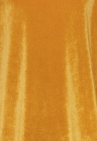 Fluwelen stof in helder goudgeel met een gladde, glanzende textuur en een lichtreflecterend oppervlak. Geschikt voor verschillende textieltoepassingen.