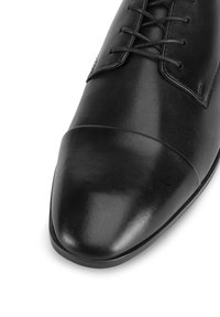 Melnas ādas vienīgai kurpes ar norādītu pirkstu, gludu virsmu un šņorēšanas detaļu. Izceļas ar kontrastējošo vāciņu un minimālistisko dizainu.