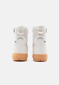 Zapatillas deportivas blancas de caña media, con parte superior de tejido texturizado y cuero liso, que presentan una suela de goma y adornos de correa de Velcro ajustable.