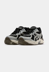 Sorte og sølv atletiske sko med netpaneler, tykke såler og dekorative detaljer. Har snører og rund tå-design.