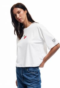 Witte korte mouwen t-shirt van katoen, met rode kersborduring op de borst en de tekst "CHERRY CHERRY LADY" op de mouw.