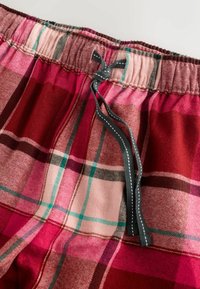 Punaiset ja vaaleanpunaiset ruudulliset pyjamahousut, joissa on joustava vyötärönauha ja harmaa nyöri, pehmeä kangaspinta ja kontrastivärinen ompelu.