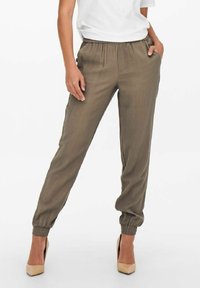 Pantalon vert olive en tissu léger, doté d'une taille élastique, de poches latérales et de poignets fuselés aux chevilles.