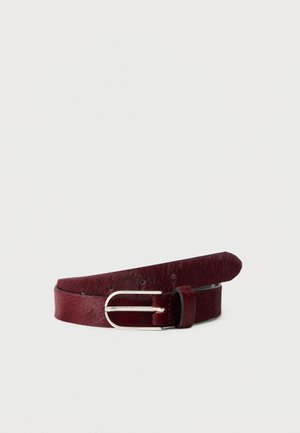 Smalle donkerrode leren riem met een zilveren metalen gesp, opgerold op een witte achtergrond.