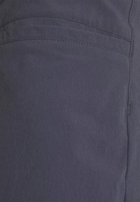 Närbild på mörkgrått tyg med synlig sömnadsdetalj och sömmar på ett plagg.