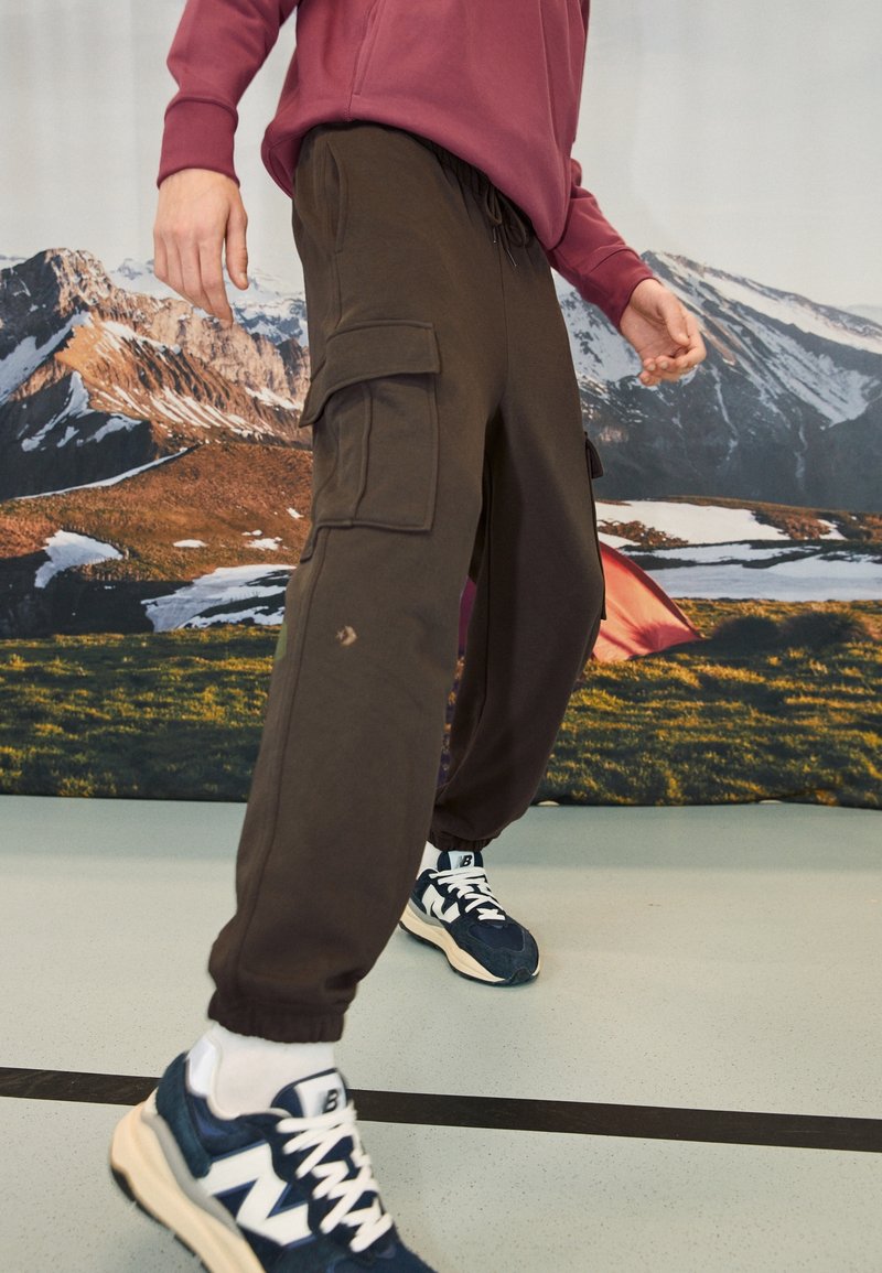 Bruine cargo sweatpants met verstelbare tailleband en elastische boorden, voorzien van twee grote zijzakken en een subtiele slijtage-detail.