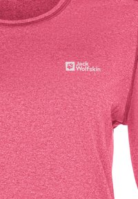 Nahaufnahme eines pinken Jack Wolfskin-Shirts, das die Stoffstruktur und das weiße Logo auf der Brust zeigt.