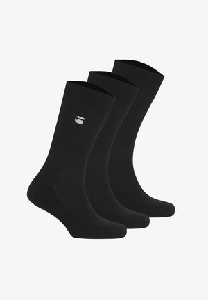 Drei schwarze Sportsocken mit einem kleinen weißen Logo an der Seite, aufrecht stehend und in einer Reihe ausgerichtet.