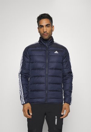 Marineblauer Steppjacke mit gestepptem Design, hohem Kragen und weißen Seitenstreifen. Vorderer Reißverschluss und Logo auf der linken Brust.