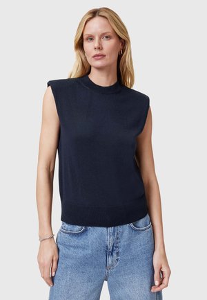 Marineblauw zondermouwen tricot top met een hoge halslijn, geribbelde zoom en schouderdetails, gecombineerd met lichtblauwe jeans. Soepele textuur.