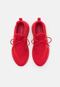 Röda sportskor i ventilerande mesh och gummi, med en texturerad yta, rund tå och snörning framtill.