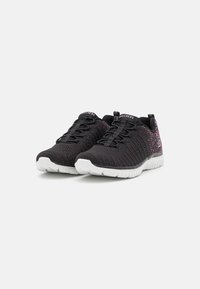 Zapatillas deportivas negras con tejido texturizado, diseño de cordones y suela de goma blanca. Salpicaduras de colores adornan el lateral. Logotipo de la marca en la lengüeta.
