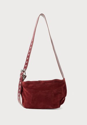 Geantă de umăr din suede bordeaux, cu un finisaj neted și o curea lată, prezentând decupaje circulare și accente metalice. Formă moale și lejeră.