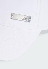 White cap made of fabric with a curved brim, featuring a metal logo plate with three stripes. Smooth texture with stitched detail.