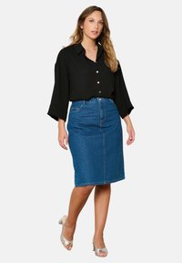 Black button-up shirt with loose sleeves, paired with a mid-length denim skirt. The skirt features a front slit and classic blue wash.