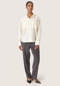 Button-up skjorte i lysegul, med en tekstureret finish og to brystlommer. Sæt sammen med skræddersyede pinstribede bukser i mørkegrå.