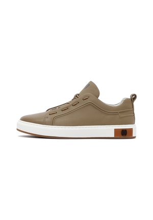 Beige leren sneaker met een witte zool, voorzien van ronde vetergaatjes en een bruine accent aan de zijkant. Glad oppervlak en laag uitgesneden ontwerp.