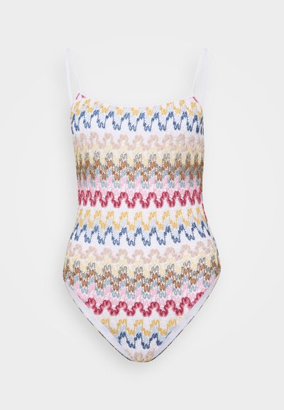 Maillot de bain une pièce avec fines bretelles, présentant un motif en zigzag bleu, rose, jaune et beige sur fond blanc. Tissu extensible, coupe medium.