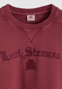 Μπλουζάκι μπορντό με ριμπ λαιμόκοψη, λεπτομέρειες με κεντημένο λογότυπο "Levi Strauss" και έμβλημα. Μαλακή υφή, σχεδιασμός με χαλαρή  εφαρμογή.